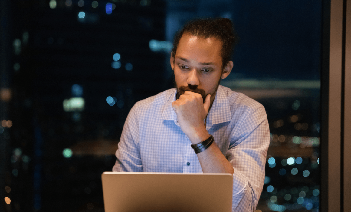 Confident man in a business suit looking at a laptop, representing the success of hiring an administrative assistant for a financial services firm.