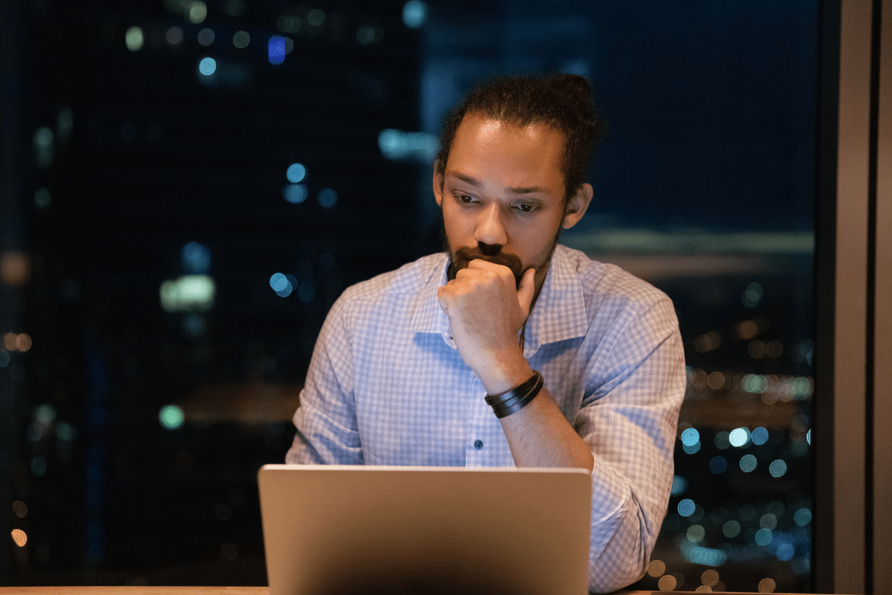 Confident man in a business suit looking at a laptop, representing the success of hiring an administrative assistant for a financial services firm.
