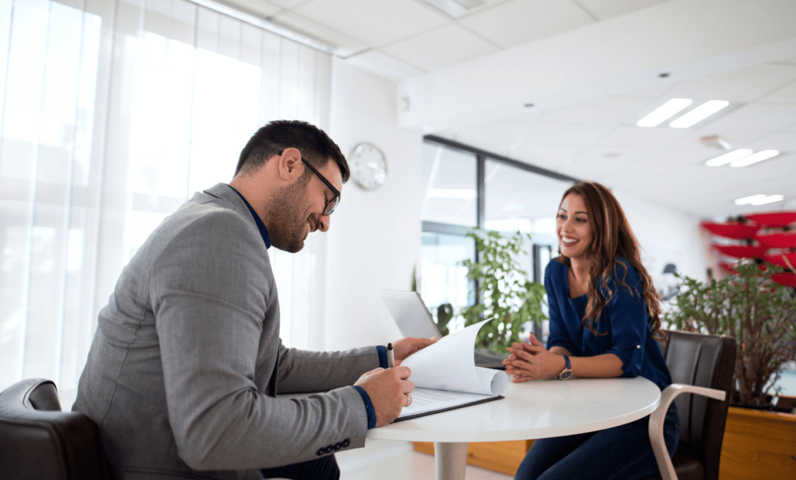 Two professionals smiling at each other in a workplace, representing employee engagement and job satisfaction